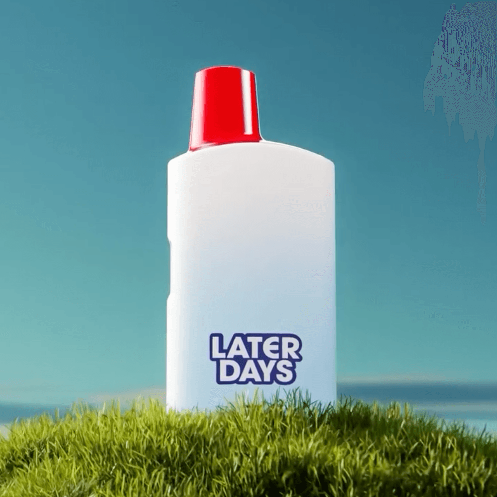 Later Days red cap disposable vape standing on grass with ocean and blue sky in NJ