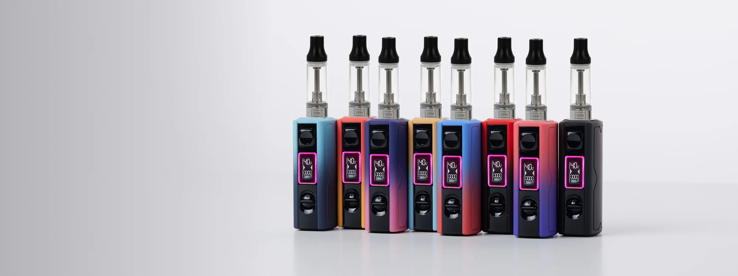 Eight vape devices in blue, red, navy, gold, and black with clear tanks and digital displays