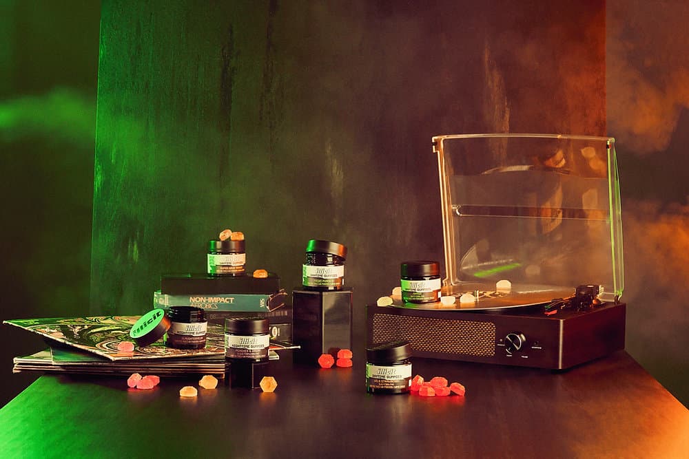 Illicit NJ jars and gummies arranged around a desktop vaporizer under green and orange lighting
